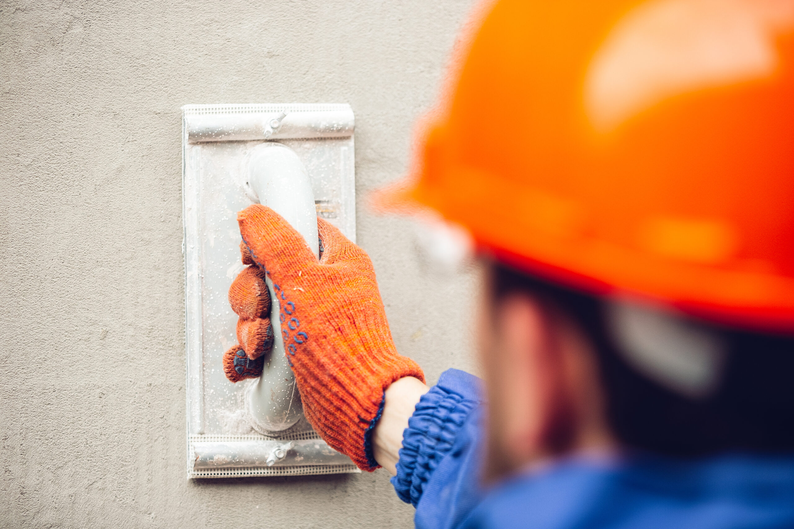 Closeup of repairman in uniform, professional builder working using construction equipment. Process of building, apartment renovation, repairing, building. Coloring, measuring, preparing the base.